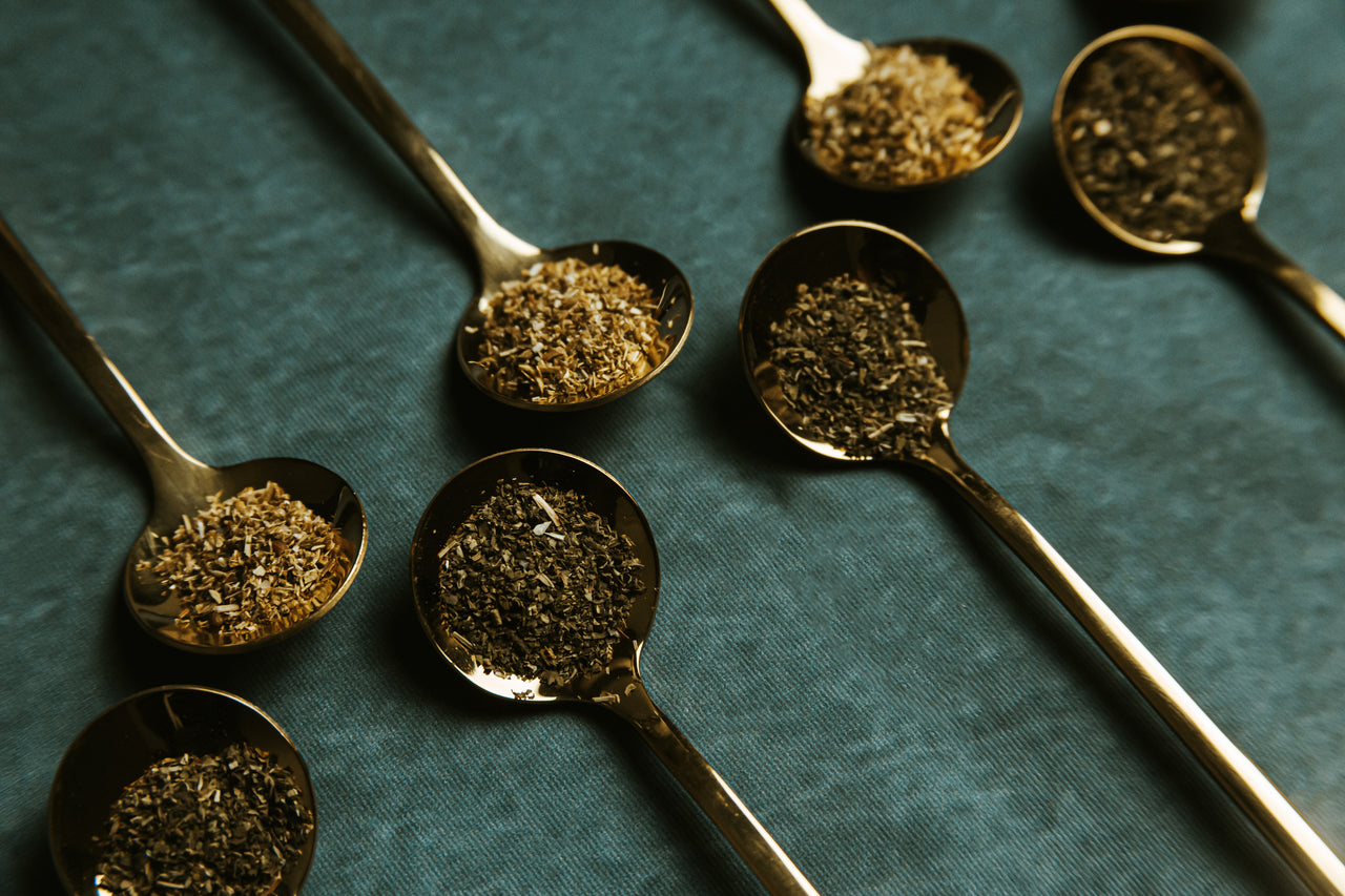 Hand-filled herbal tea bags hanging against a black background